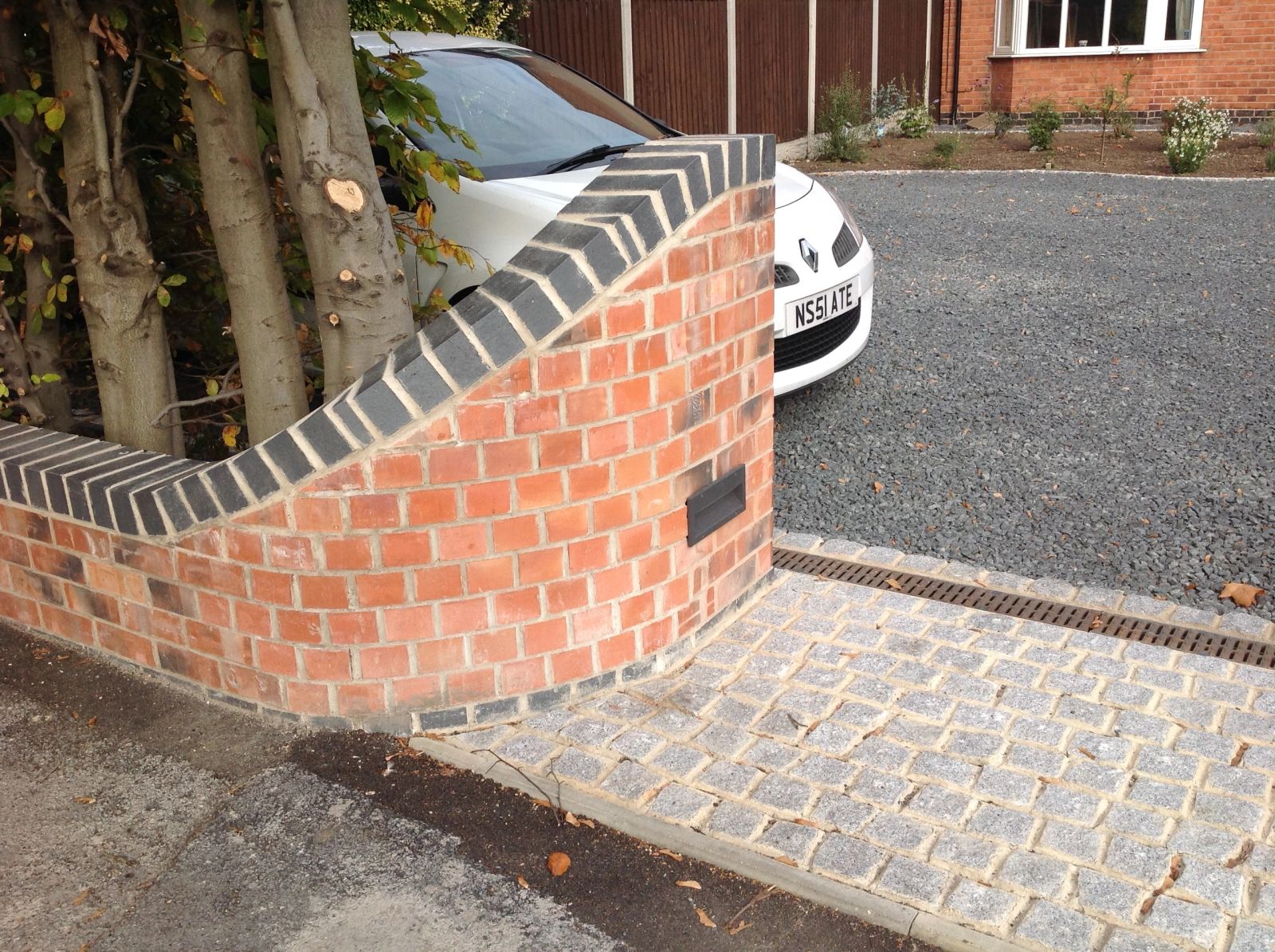 Curved brick wall with block paving and drainage channel